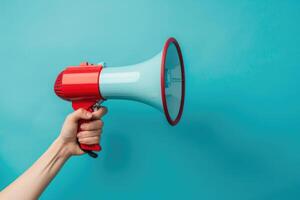 Hand holding a red and blue megaphone against a blue background photo