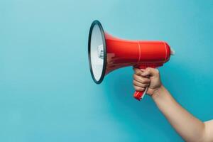 Hand holding a red megaphone on blue background photo