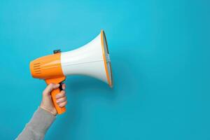 Hand holding a megaphone against blue background photo