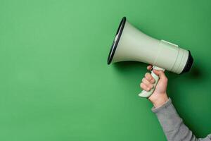 Hand holding a megaphone against a green background photo
