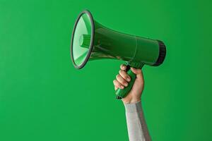 Hand holding a green megaphone on a green background photo