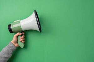 Hand holding a megaphone on a bright green background photo