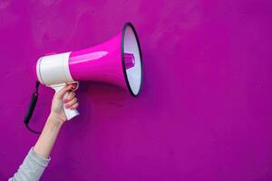 Pink megaphone in hand against purple wall background photo