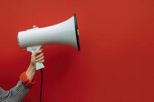 Hand holding a megaphone against a red background photo