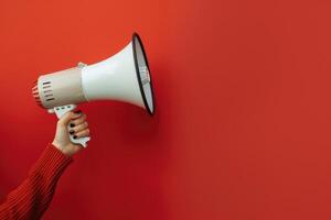 Hand holding a megaphone against a red background photo