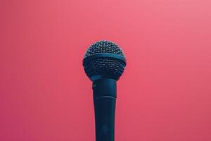 Closeup of a black microphone against a pink background photo