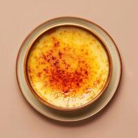 Close up of a creamy Creme Brulee with a perfectly caramelized sugar crust, served on a pink saucer with a pink background. photo