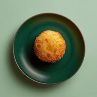 Crispy and golden deep-fried mozzarella ball on a green plate. Delicious appetizer or snack for food blog or restaurant menu. photo