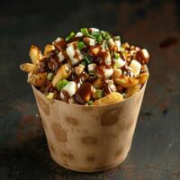 Close up of Poutine in a paper container with cheese curds, gravy, and fries. Classic Canadian comfort food on a dark background. photo