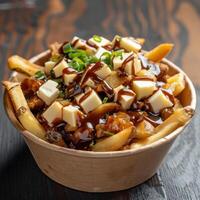 Delicious Poutine, Canadian comfort food with french fries, cheese curds, and gravy. Close up view of traditional dish in a paper bowl photo