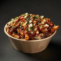 Canadian poutine with cheese curds, gravy and fries in a paper bowl. Food photography with a black background. photo