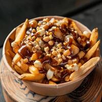 Close-up of a poutine dish with cheese curds, gravy, and fries in a paper bowl. photo