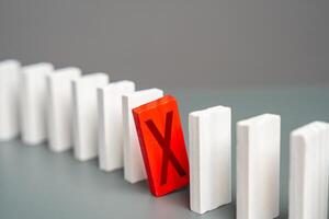 The red domino with a cross hinders the whole process. Breakdown. Out of service. Sanctions. Stop work. Refusal and protest. Critical error. Unavailability. Unfulfilled plans. Negative review photo