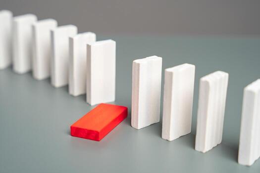 A domino that has fallen out of a row of standing dominoes. Out of order. Health problems. Weak link. Burnout at work. Violation of integrity. Stoppage of work. Cause of possible disaster. photo