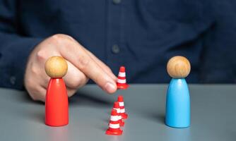 A man sets up a barrier of cones between people in conflict. Concept of the demarcation line. Freezing the conflict. Finding solutions. Reconciling the parties. Acting as a mediator. photo