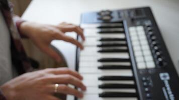 Recording music notes, playing electronic keyboard, midi keys in music sequencer. Hands and midi controller on the table, man composing music, blur photo