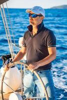 Young man captain stands at the helm and controls a sailboat during a journey by sea. High quality photo