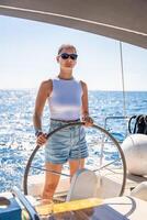 Young woman female captain stands at the helm and controls a sailboat during a journey by sea. High quality photo
