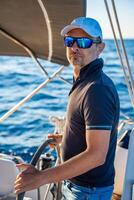 Young man captain stands at the helm and controls a sailboat during a journey by sea. High quality photo
