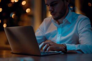 a man in a white shirt is typing on a laptop photo