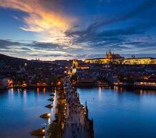 Night view of Prague castle and Charles Bridge over river photo