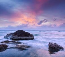 Waves and rocks on beach of sunset photo
