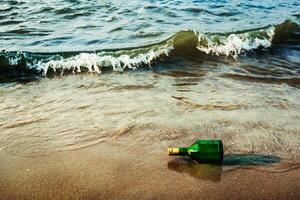 Message bottle on beach in waves photo