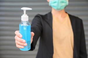 Shot of woman holding a hand sanitizer before using it. photo