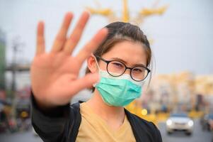 Woman wearing surgical mask for protect bad air pollution or virus and show stop hand gesture for social distancing. photo