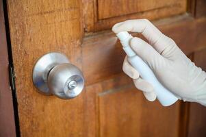 Shot of someone hand using alcohol hand sanitizer spraying on the door knob before open it. Hand sanitizer used to decrease infectious or kills germs, bacteria even more coronavirus. photo