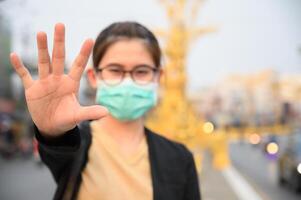 Woman wearing surgical mask for protect virus and show stop hand gesture for social distancing. photo