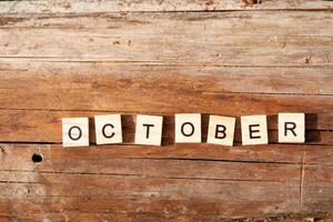The word october is written in wooden letters on a wooden background. Autumn concept and calendar concept. Copy space photo