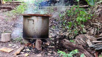 Image of a stainless steel pot boiling on a fire stove, with smoke billowing. photo