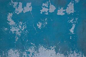 Peeling paint and cracked blue wall texture background. Weathered decayed urban surface with chipped paint and cracks. Distressed, rustic aesthetic for graphic design, web design, digital art. photo