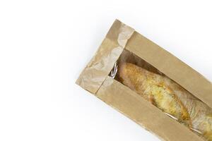 Freshly baked French baguette in a brown paper bag isolated on a white background.Loaf of white bread wrapped in eco-friendly sustainable brown paper bag. Copy space. With clipping path. photo