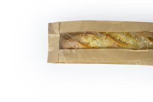 Freshly baked French baguette in a brown paper bag isolated on a white background.Loaf of white bread wrapped in eco-friendly sustainable brown paper bag. Copy space. With clipping path. photo
