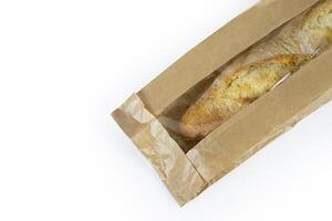 Freshly baked French baguette in a brown paper bag isolated on a white background.Loaf of white bread wrapped in eco-friendly sustainable brown paper bag. Copy space. With clipping path. photo