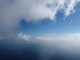 Aerial view. The drone flies over foggy and fluffy clouds. Blue sky sun and sea fog. Abstract aerial nature summer ocean sunset sea and sky background. Vacation, travel and holiday concept photo