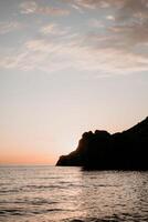 A red burning sunset over the sea with rocky volcanic cliff. Abstract nature summer or spring ocean sea background. photo