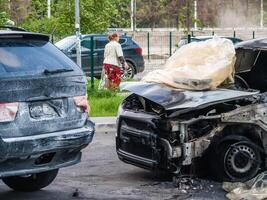 Broken and burned cars in the parking lot, accident or deliberate vandalism. Burnt car. Consequences of a car accident. Damaged by arson. Dump of civilian vehicles shot by Russian troops in Ukraine. photo