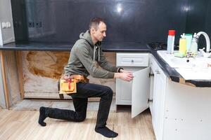 Older man disassembling apartment kitchen out of service photo