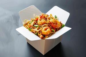 Wok with shrimps and vegetables in a takeaway box on dark background photo