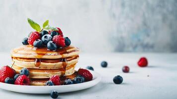 Delicious Stack of Fluffy Pancakes Topped With Fresh Berries and Maple Syrup on a Light Background photo