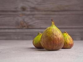 Ripe figs fruit are on a cement floor with a wooden wall background. High Vitamins fruit. Space for text. Healthy fruits and healthcare concept photo