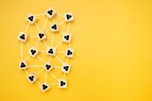 Network, Teamwork, and unity concept. Top view of wooden blocks with black human icons laid scattered on a yellow background, Flat lay, space for text photo