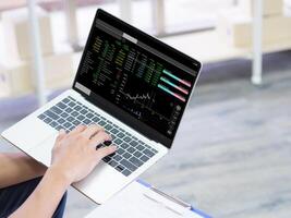 Close-up of businessman analyzing data stock market on a laptop at workplace in the office. Financial investment concept photo