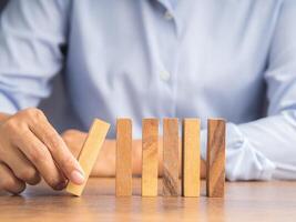 Close-up of hand push a wooden block on a line of domino. Risk and strategy in business concept photo