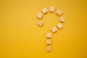 Question mark concept with arranging wooden blocks isolated yellow background with space for text photo