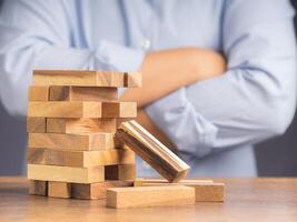 Man arms crossed looking at wooden block game while sitting at the work table. Concept Risk of management and strategy plans for business growth and success photo