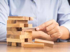 Close-up hand of the businessman playing wooden block game while sitting at the work table. Concept Risk of management and strategy plans for business growth and success photo